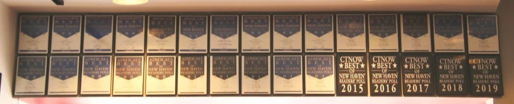 Two rows of Best of New Haven readers’ poll plaques on a wall, ending with CTNOW plaques for 2015, 2016, 2017, 2018 and 2019