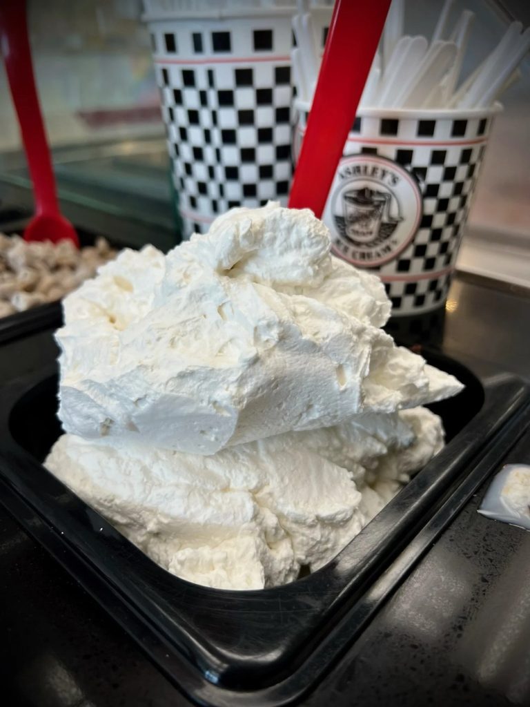 A heaping tray of fresh whipped cream at the Ashley’s Ice Cream counter, with checkered cups behind it