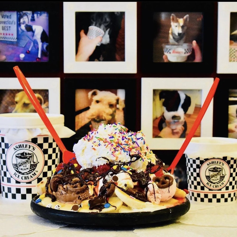 A giant Ashley’s sundae piled with whipped cream, rainbow sprinkles and chocolate sauce, with red spoons in checkered tubs
