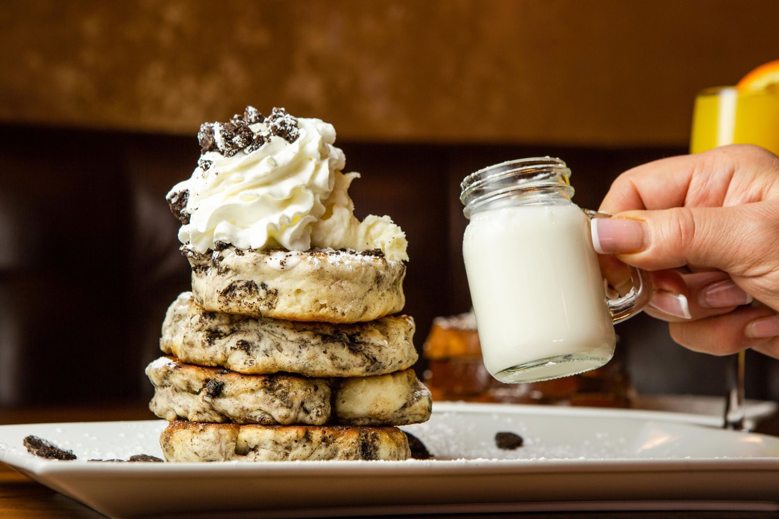 A stack of pancakes topped with whipped cream at Bella’s Cafe