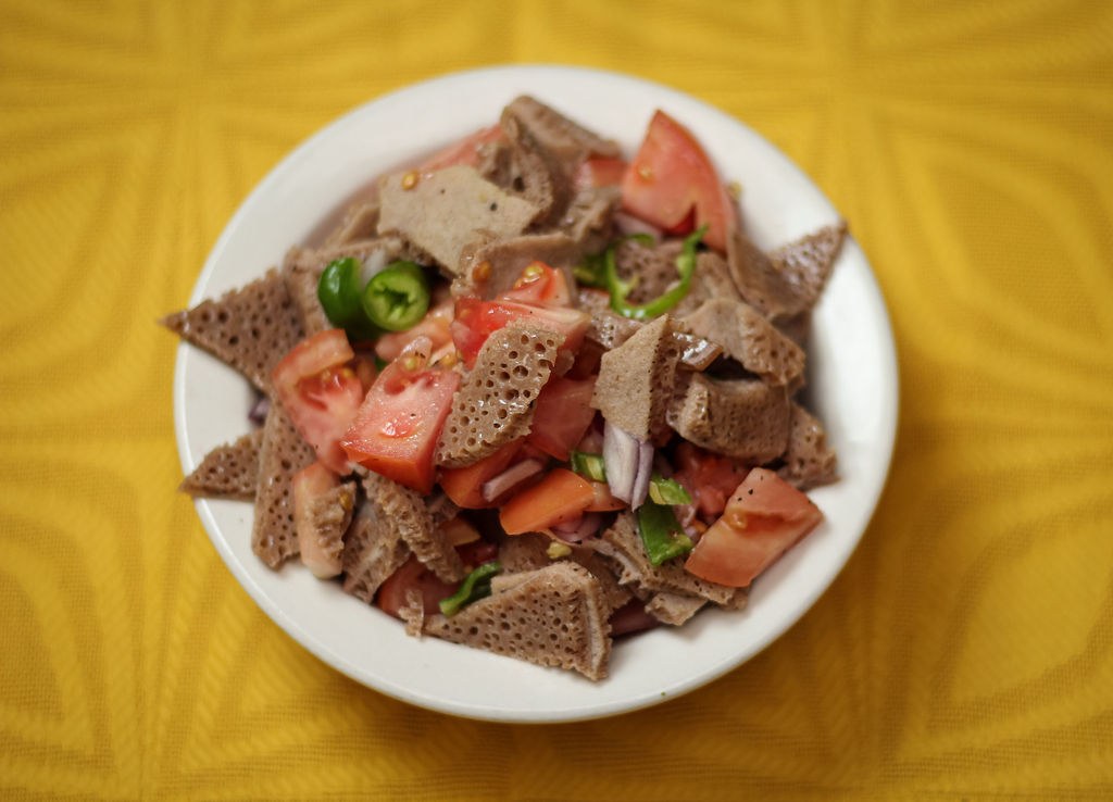 Lalibela’s timatim fitfit, torn injera tossed with chopped tomatoes and green peppers on a white plate