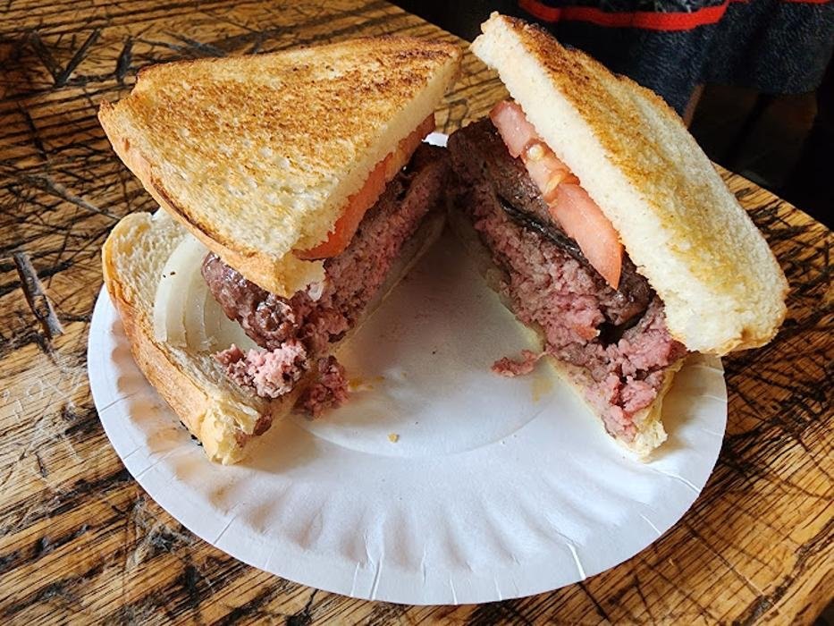 A Louis’ Lunch burger with tomato and onion on toast, cut in half