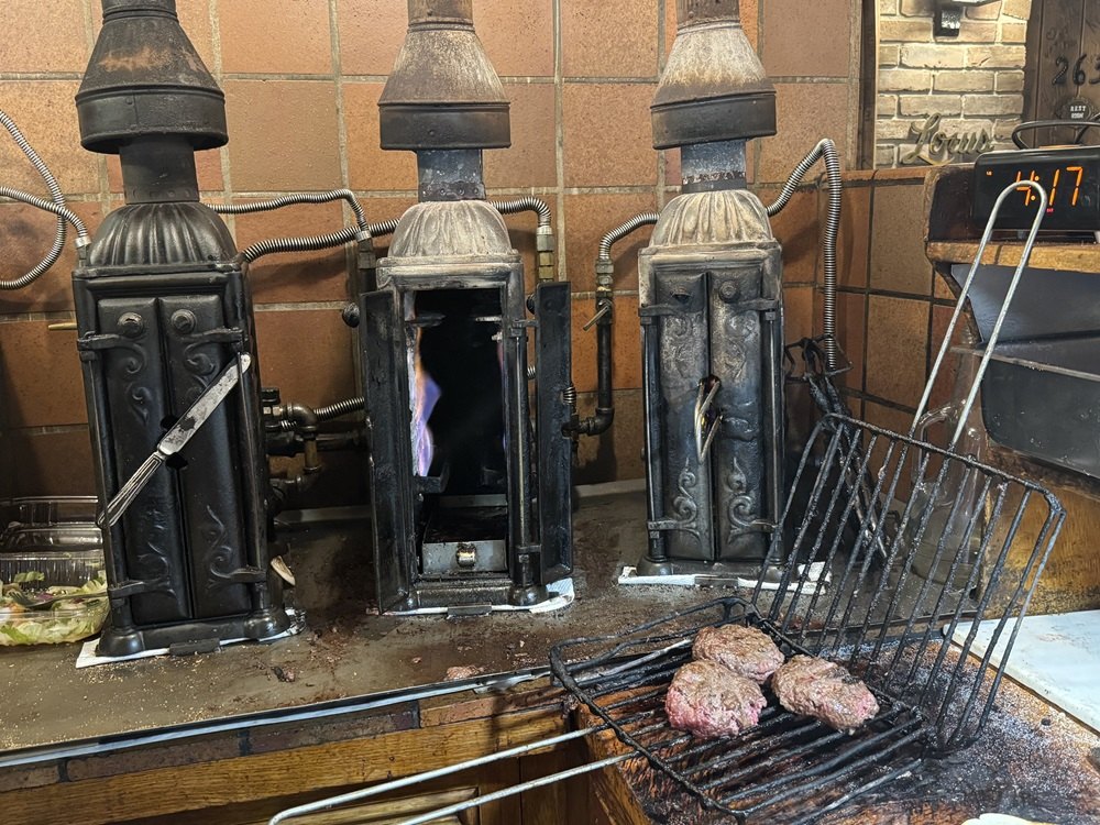 Three antique vertical cast-iron broilers and a rack of burgers at Louis’ Lunch