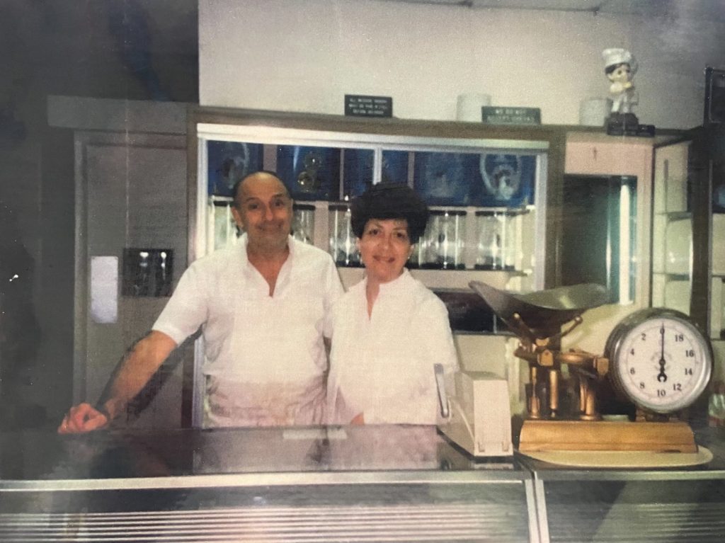 A vintage photo of a couple standing behind the counter at Lucibello’s, from the shop’s history page
