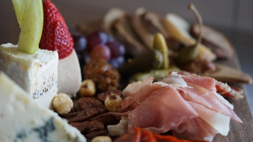 A cheese and charcuterie board with prosciutto, cheeses and fruit at Shell & Bones