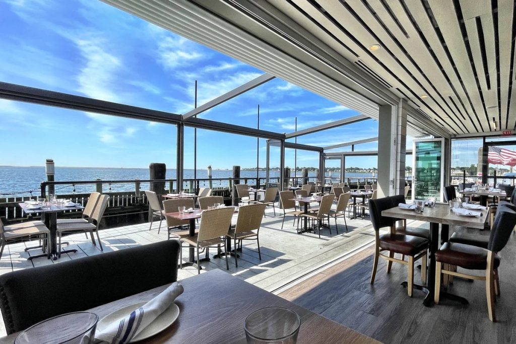 The covered outdoor deck at Shell & Bones, with tables looking out over New Haven Harbor