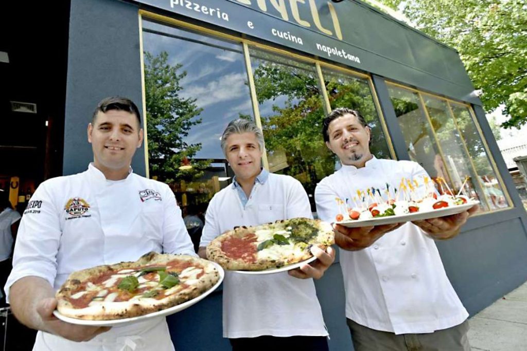 Three Zeneli brothers outside the Wooster Street restaurant, holding pizza and antipasto